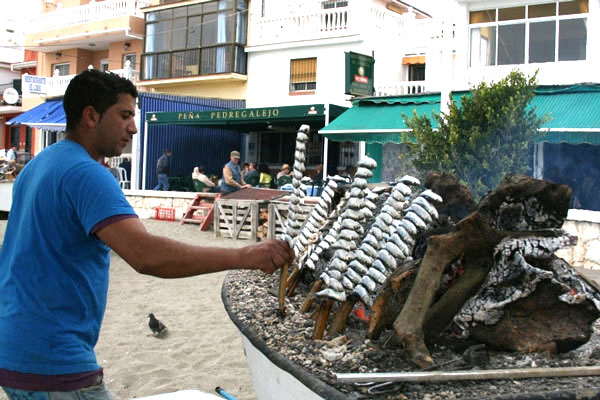 Typischer Strandgrill namens Chiringuito in Andalusien Mann grillt Sardinen am Strand