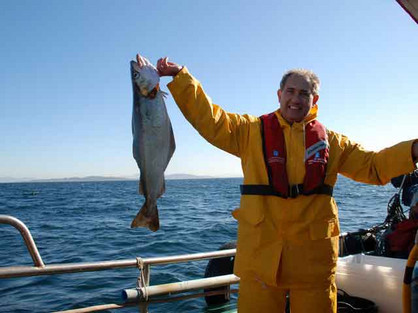 Mann zeigt Fisch auf Boot in Galicien, Nordwestspanien